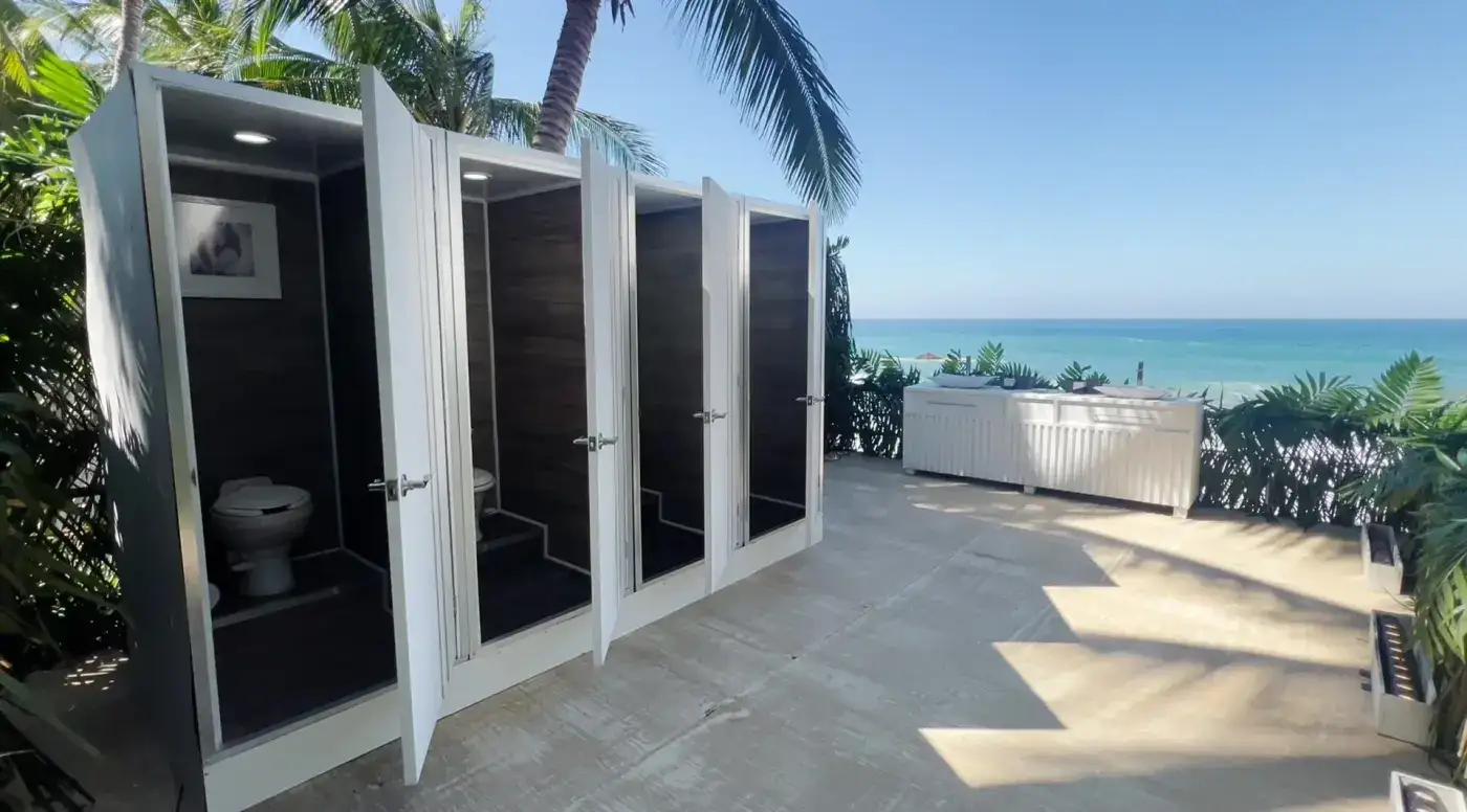 Baños portátiles VIP de lujo frente al mar con palmeras, unidades premium y lavamanos exteriores para evento exclusivo — Luvory
